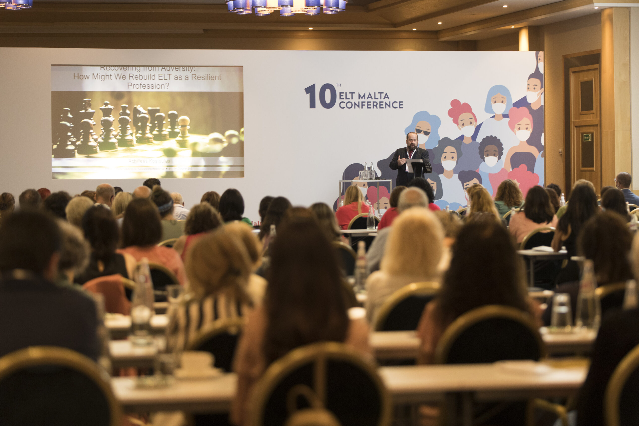 A big room full of people with a man addressing the room.